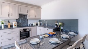 A modern kitchen with white cabinets, a granite countertop, and a built-in oven. - The Stables - UK49089 (Crediton)