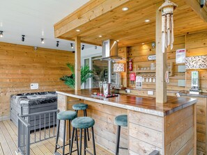 A wooden interior with a bar area, bar stools, a couch, and a fire extinguisher.