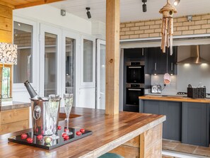A modern kitchen with dark cabinets, a wooden countertop, and a hanging light fixture. - 2 bedroom accommodation in Minehead, near Somerset (Minehead, near Somerset)