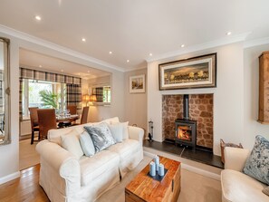 A living room with a fireplace, a sofa, a coffee table, and a dining area with a table and chairs. - 2 bedroom accommodation in Minehead, near Somerset (Minehead, near Somerset)