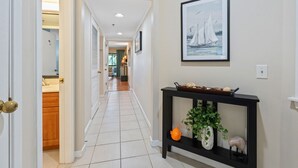 A hallway with a black console table, a framed painting, and a door leading to a kitchen.