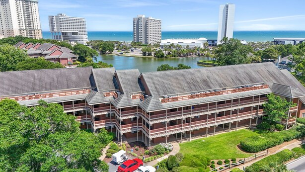 A multi-story hotel with a central courtyard, surrounded by greenery and a lake.