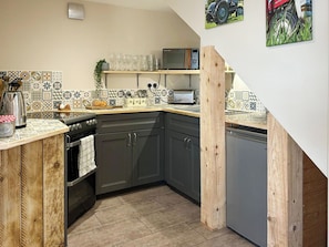 A compact kitchen with dark cabinets, a wooden countertop, a microwave, a toaster, and a sink.