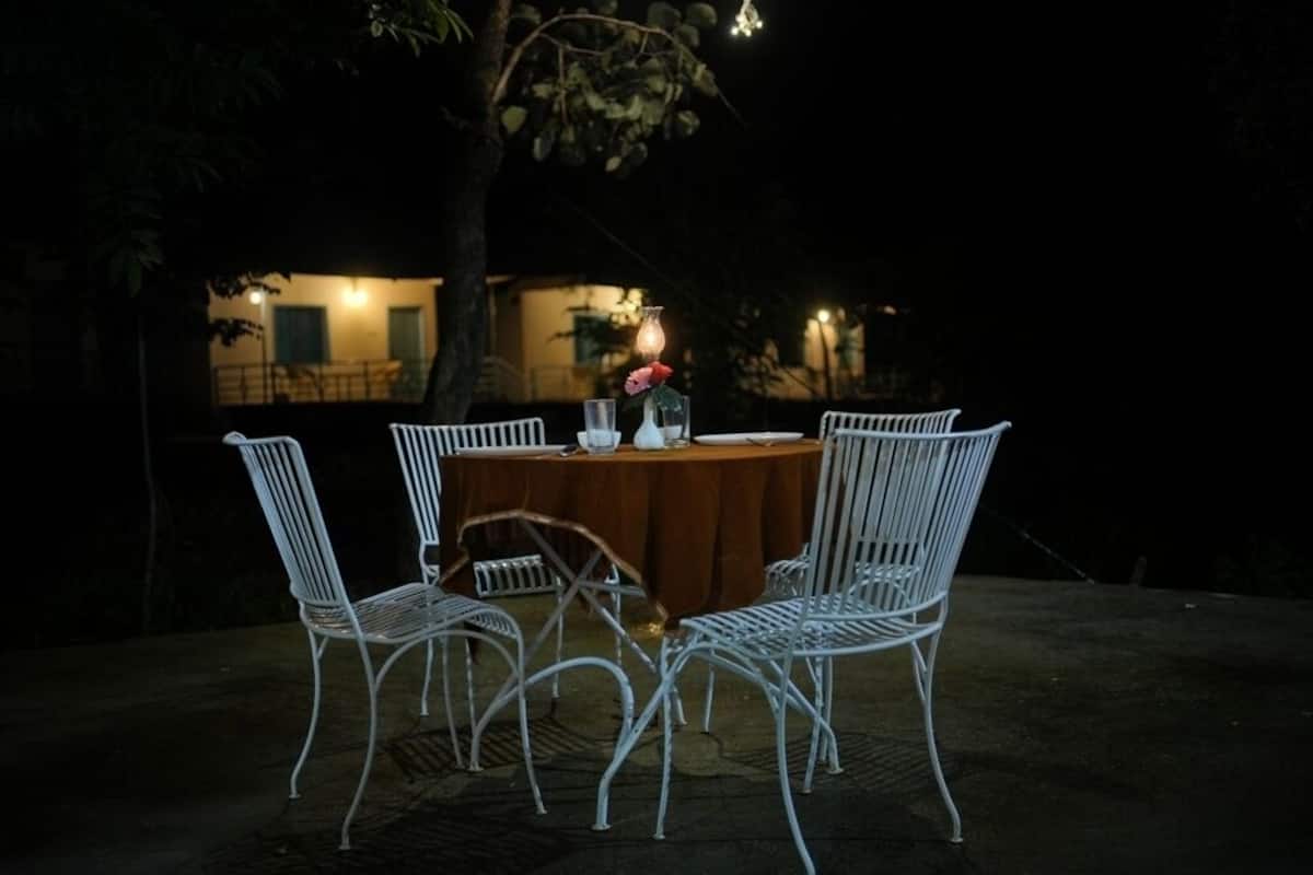 Un área de comedor al aire libre con una mesa redonda y cuatro sillas de metal blancas.