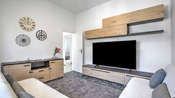 Ein modernes Wohnzimmer mit Flachbildfernseher, Holzschnellschränken und dekorativen Wanduhren.
