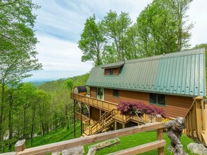 Eine Holzhütte mit einer Veranda, einer Treppe und Blick auf den umliegenden Wald.