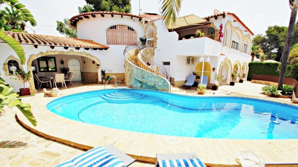 Un área de piscina con sillas de descanso y una escalera en espiral que lleva a un segundo piso.