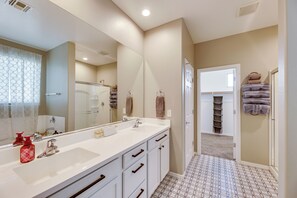 Une salle de bain avec un grand miroir, deux lavabos et un porte-serviettes.