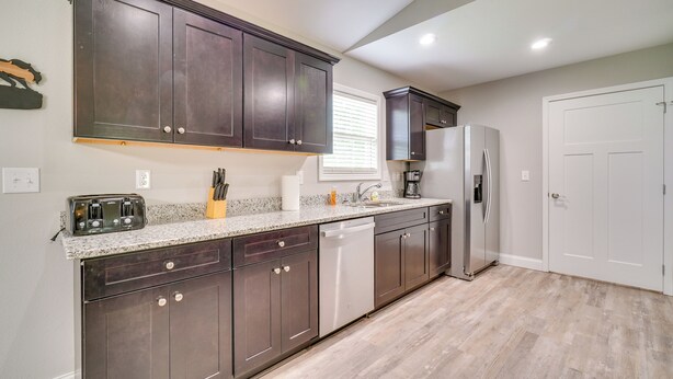Una cocina moderna con armarios de madera oscura, un refrigerador de acero inoxidable y un lavavajillas.