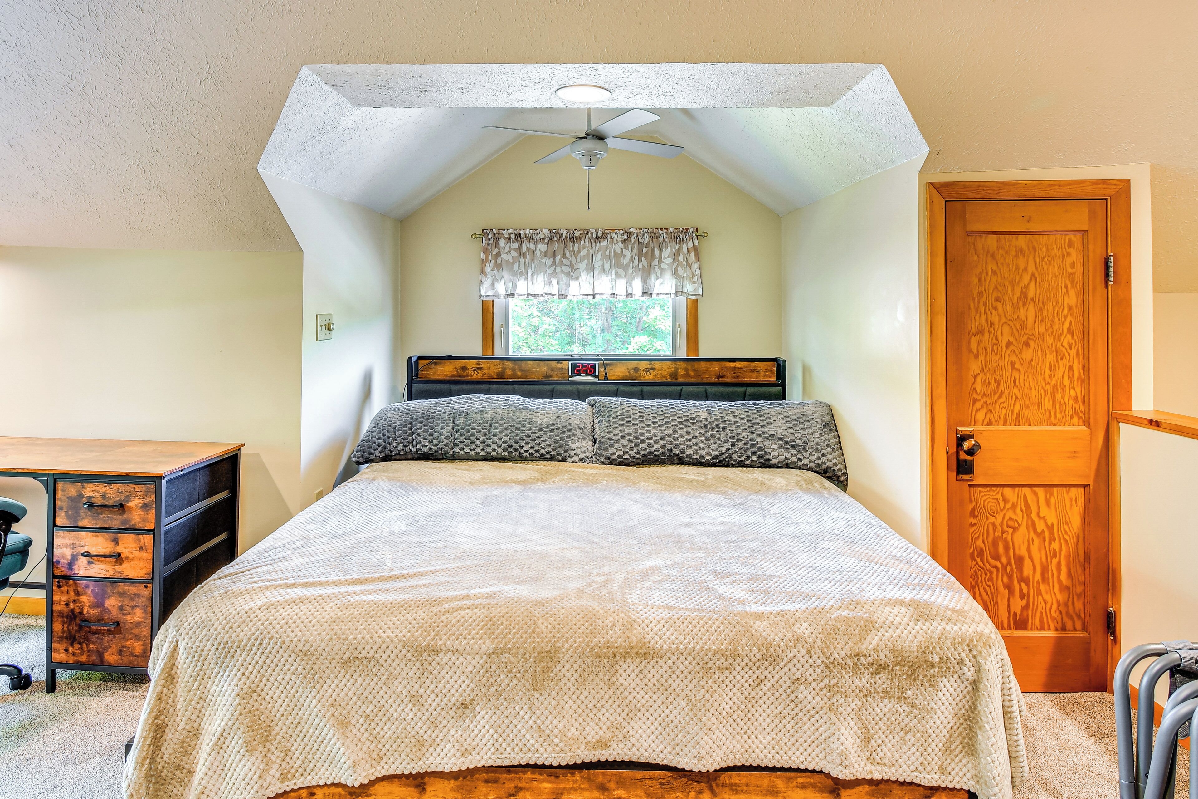 Une chambre à coucher avec un lit, un bureau et une fenêtre avec un rideau.