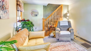 Een woonkamer met een bank, fauteuil en een trap.