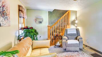 Un salon avec un canapé, un fauteuil et un escalier.