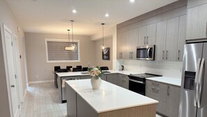 A modern kitchen with a central island, stainless steel appliances, and a dining area with a table and chairs.