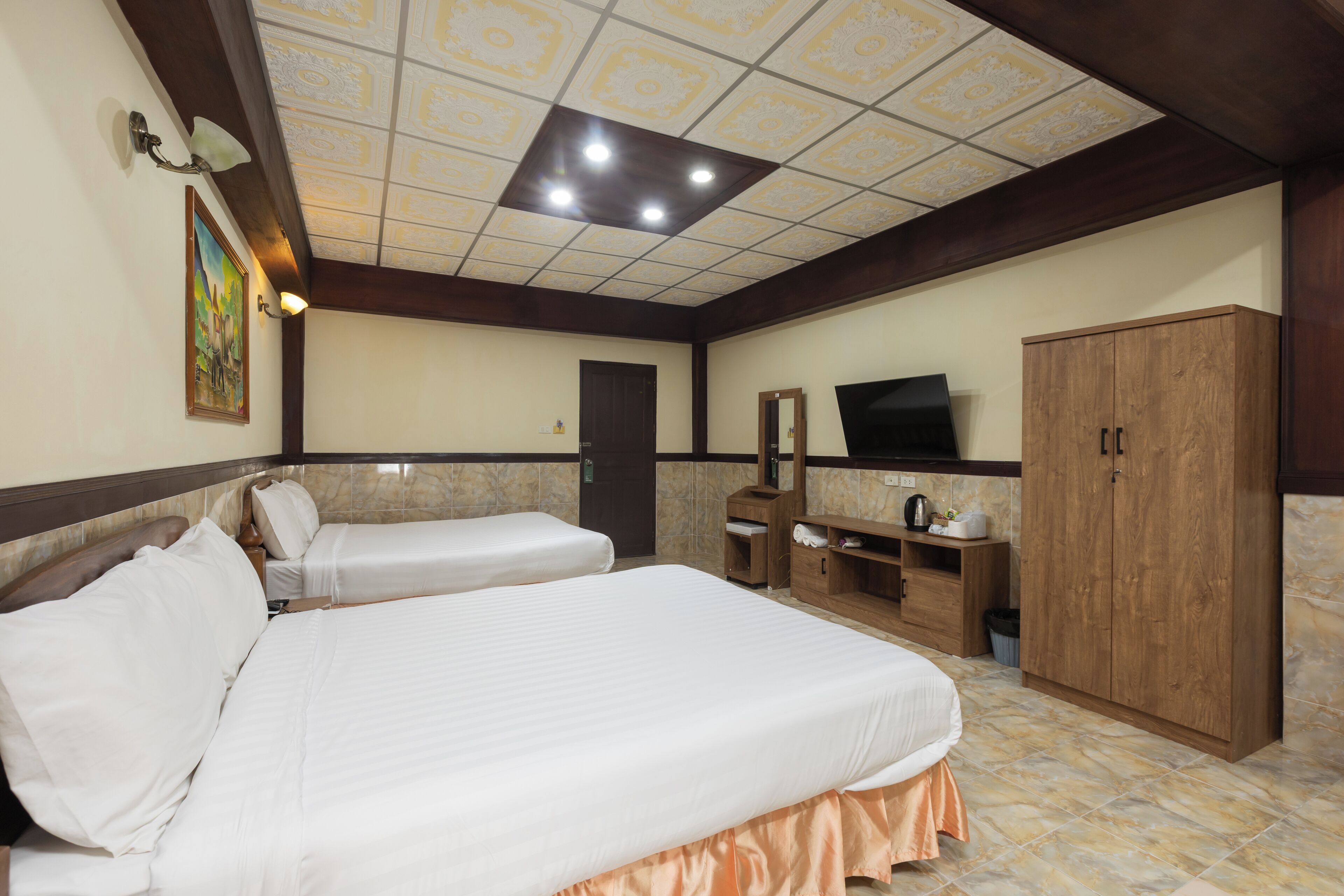 A hotel room with two beds, a wooden wardrobe, a television, and a bathroom.