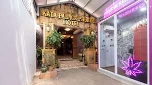 La entrada al Kata Palace Phuket Hotel, con fachada de madera y plantas en macetas.