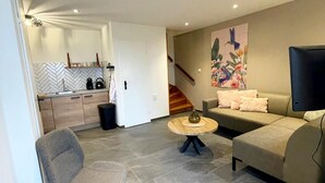 A modern living room with a grey sofa, a round coffee table, and a TV. - Holiday Home in Voerendaal With Terrace (Voerendaal)