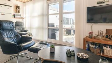 A modern living room with a leather sofa, a round coffee table, and a television mounted on the wall.