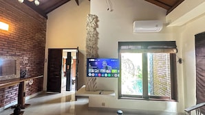 Un interior moderno con pared de ladrillo, un banco de madera, un televisor de pantalla plana montado en la pared y una ventana con vistas al exterior.