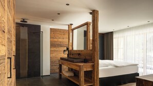 A modern bathroom with a wooden vanity, a large mirror, and a shower area.