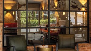 A cozy seating area with two chairs and a small round table, a large window with a view of the outdoors, and a brick wall with exposed beams. - Vacation apartment 9, 50sqm, your place to feel good (Reit im Winkl)