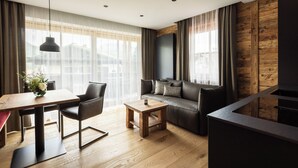 A modern living room with a wooden floor, a sofa, a coffee table, and a dining area with a table and chairs. - Vacation apartment 4, 60 sqm, with high-quality furnishings (Reit im Winkl)