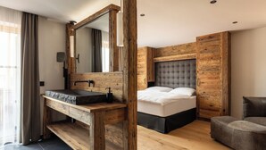 A modern bedroom with a wooden vanity, a large mirror, a bed with a tufted headboard, and a grey upholstered bench. - Vacation apartment 4, 60 sqm, with high-quality furnishings (Reit im Winkl)