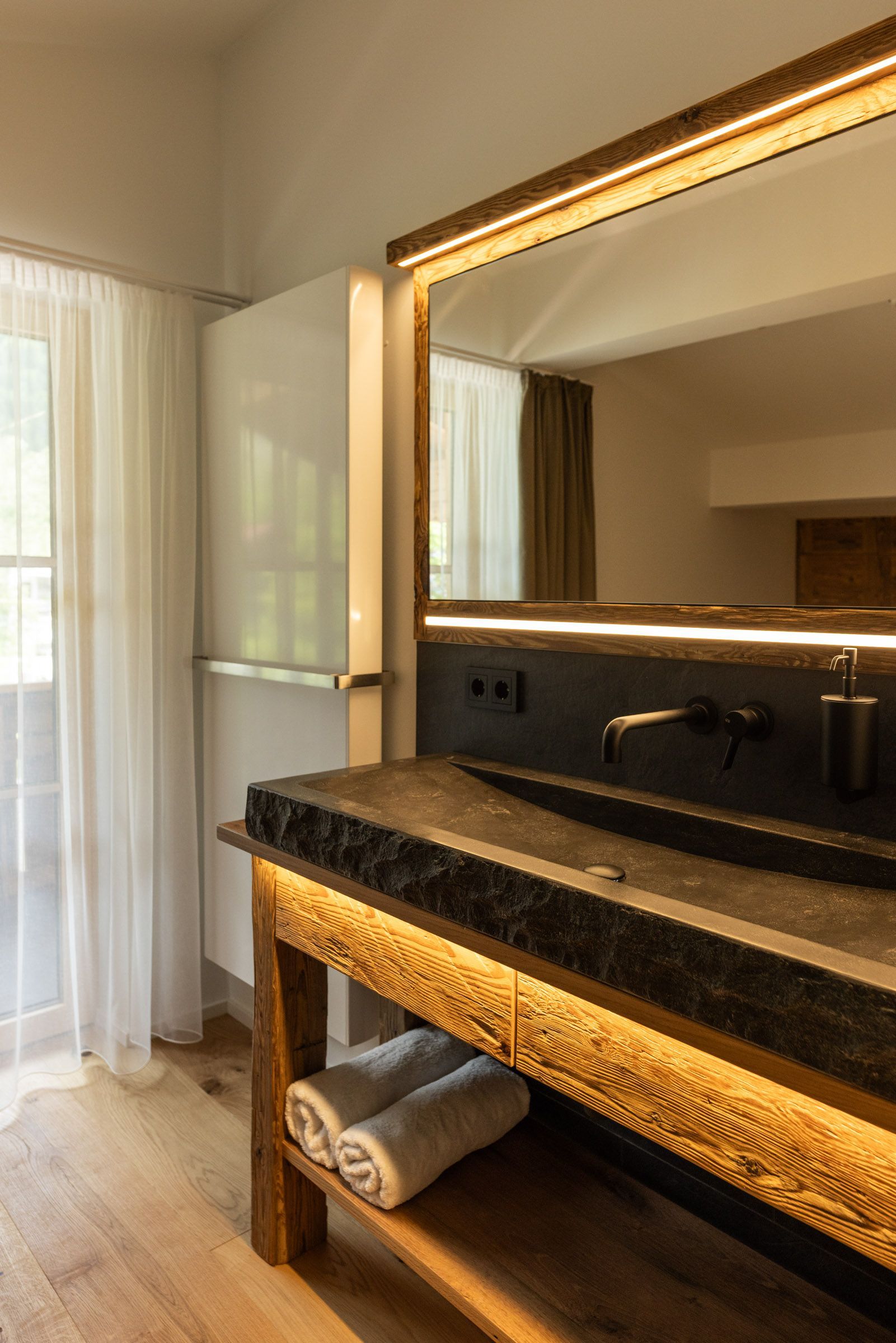 A bathroom with a wooden vanity, a large mirror, and a towel rack.