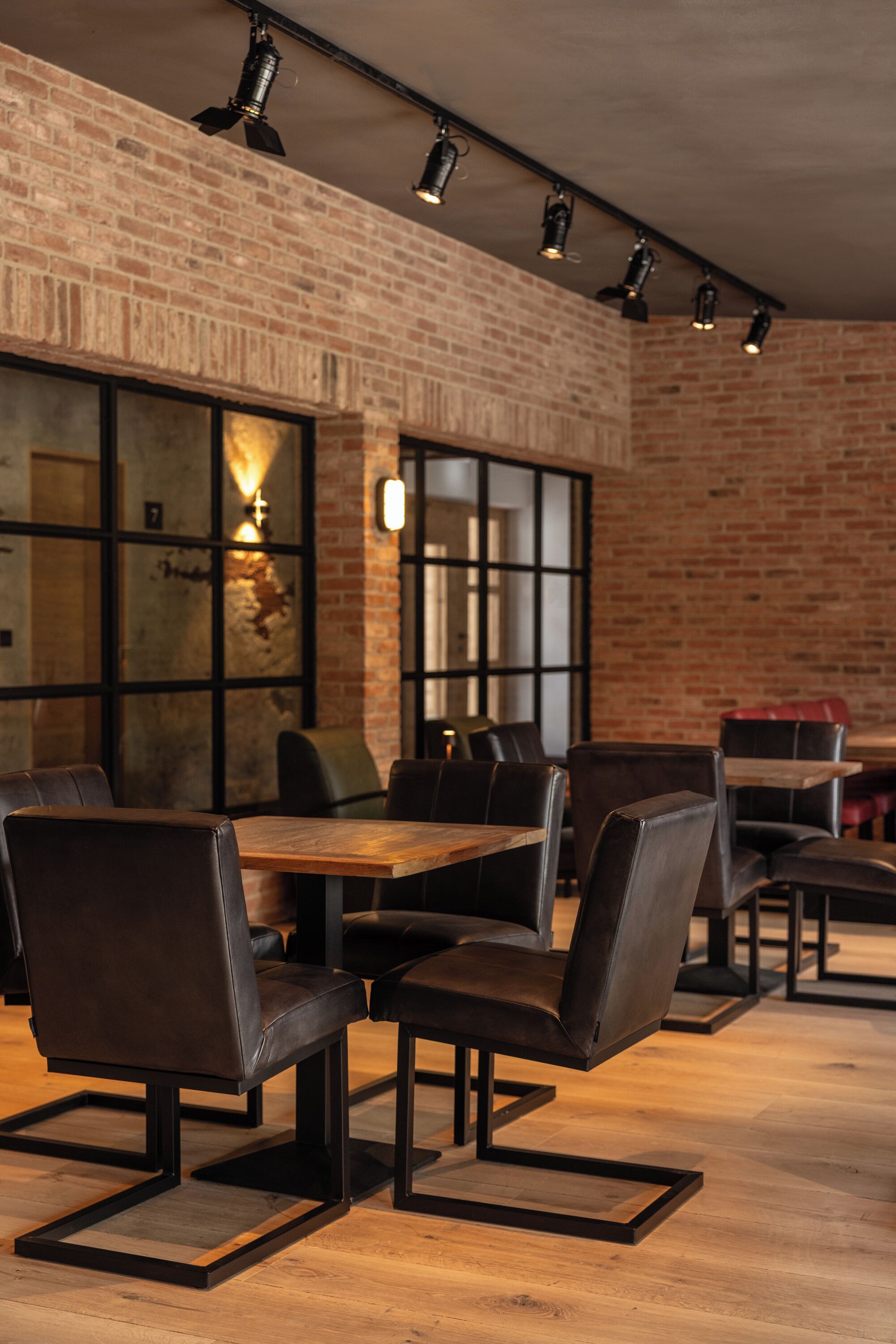 A restaurant with brick walls, wooden tables, and leather chairs.