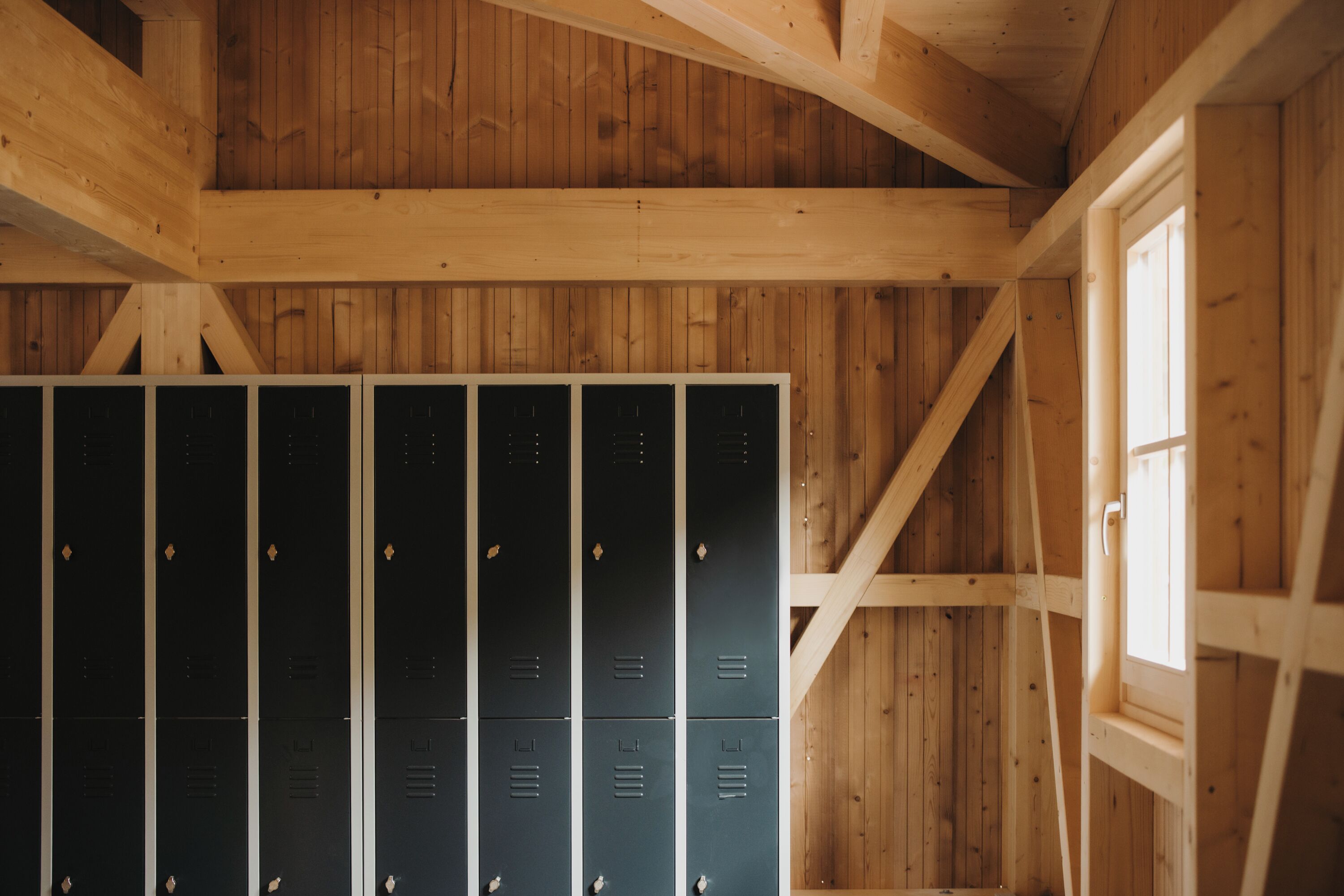 A wooden interior with multiple dark-colored lockers and a window on the right.