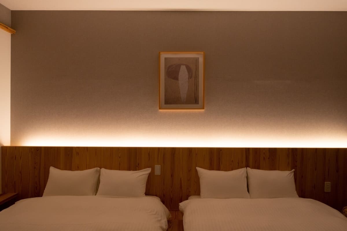 A hotel room with two beds, wooden headboard, and a framed artwork on the wall.