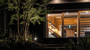 A modern building with a wooden interior, a staircase, and a view of the surrounding greenery. - Beppu Hotel Negura (Beppu)