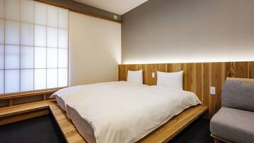 A room with a bed, a wooden bench, a sofa, and a shoji screen.