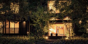 A two-story wooden house with a balcony, surrounded by dense foliage. - Beppu Hotel Negura (Beppu)