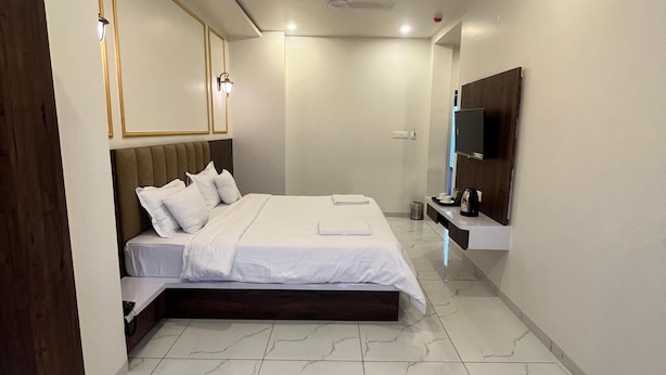 A modern bedroom with a large bed, a built-in TV, and a marble floor. - Jeel Pearl Hotel (Udaipur)