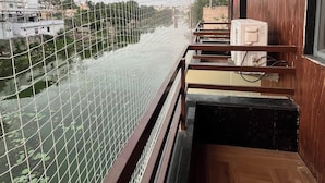 A balcony with a view of a river, a wooden railing, and an air conditioning unit on the wall. - Jeel Pearl Hotel (Udaipur)