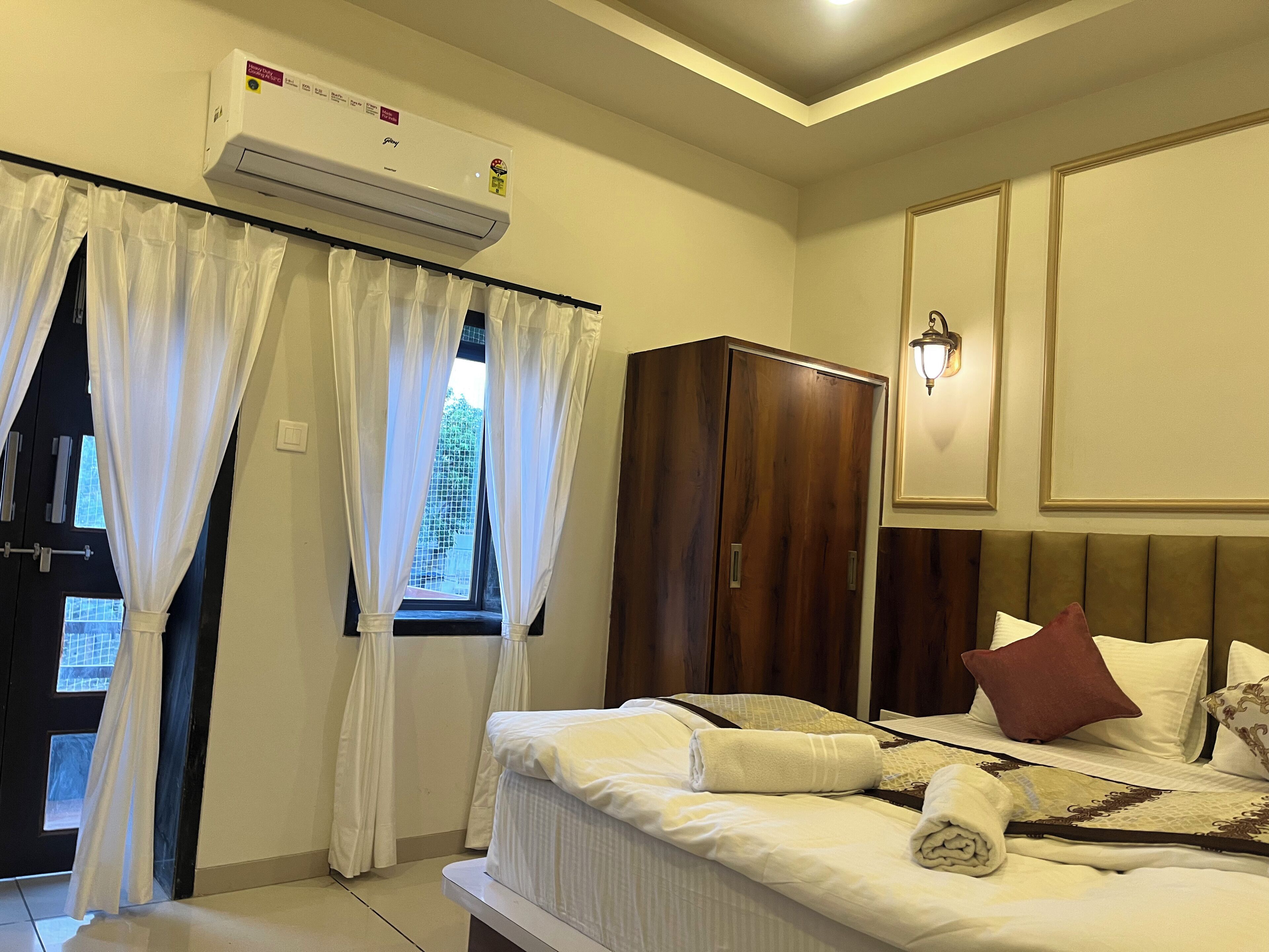 Une chambre d’hôtel équipée d’un lit, d’une armoire, d’un climatiseur et d’une fenêtre avec des rideaux.
