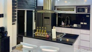 A modern kitchen with a central island, stainless steel appliances, and a chandelier. - Spacious 3-bedroom hotel suites with AC, WiFi in enjoyable City of Santa Rosa (City of Santa Rosa)