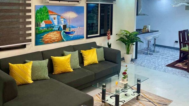 A modern living room with a sectional sofa, a glass coffee table, and a dining area with bar stools. - Spacious 3-bedroom hotel suites with AC, WiFi in enjoyable City of Santa Rosa (City of Santa Rosa)