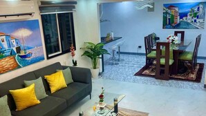 A modern living room with a dark sofa, a glass coffee table, and a dining area with a glass table and chairs. - Spacious 3-bedroom hotel suites with AC, WiFi in enjoyable City of Santa Rosa (City of Santa Rosa)