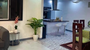 A modern living room with a dining area, a kitchen with a stainless steel hood, and a large window. - Spacious 3-bedroom hotel suites with AC, WiFi in enjoyable City of Santa Rosa (City of Santa Rosa)