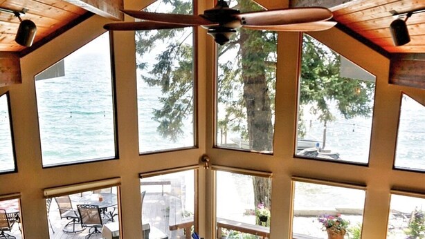 Une pièce spacieuse avec de grandes fenêtres, un ventilateur de plafond et une vue sur l’extérieur.