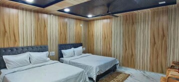 A bedroom with two beds, wooden panel walls, and a ceiling fan.