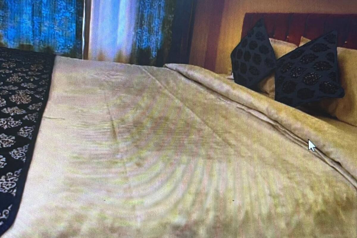 A bed with a patterned bedspread and two decorative pillows.