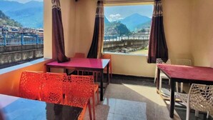 A balcony with a table and chairs, a view of mountains, and a railing. - Hotel Ganga Sagar (Bhatwari)