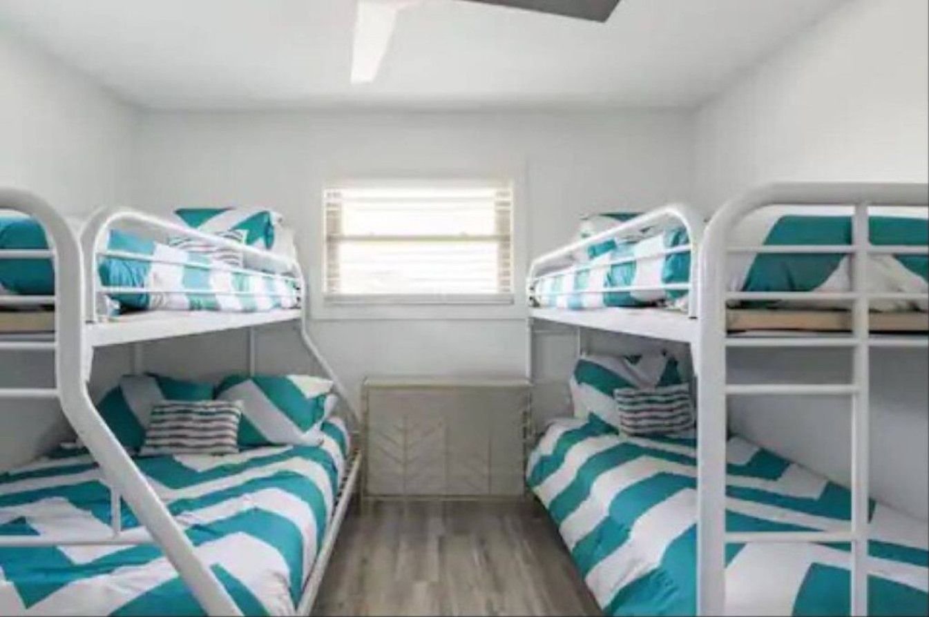 A room with bunk beds, a window with blinds, and a radiator.