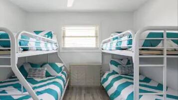 A room with bunk beds, a window with blinds, and a radiator.