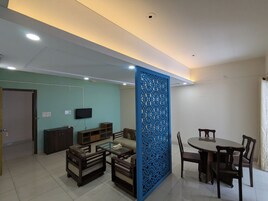 Uma sala de estar com televisão, sofá, mesa de centro e um espaço de jantar com cadeiras e mesa.
