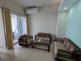 Uma sala de estar com sofá, mesa de centro e ventilador de teto.