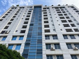 Um edifício alto com fachada de vidro central, vários aparelhos de ar condicionado e um padrão de janelas simétrico.
