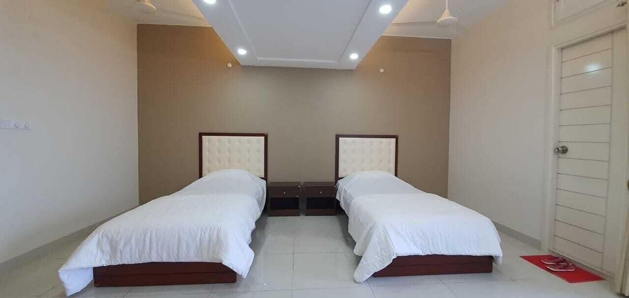 A twin room with two beds, a door, and a red mat on the floor.